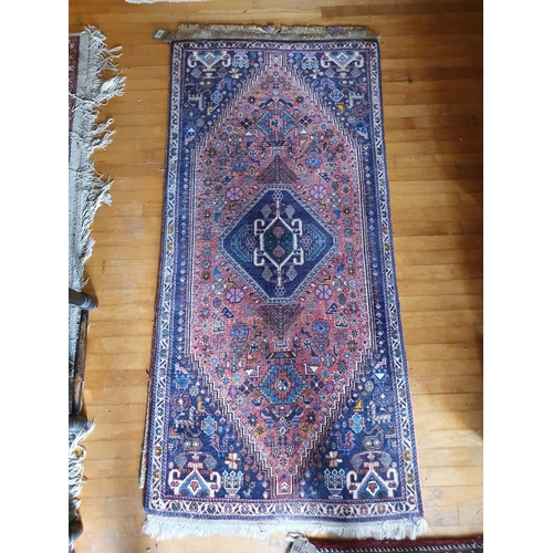 A small Persian rug, with a central lozenge on a salmon pink ground