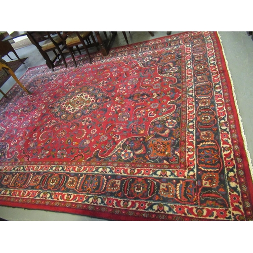 569 - Large red ground Persian Mashad carpet with floral medallion designs. 392 x 370cm approximately.
(B.... 
