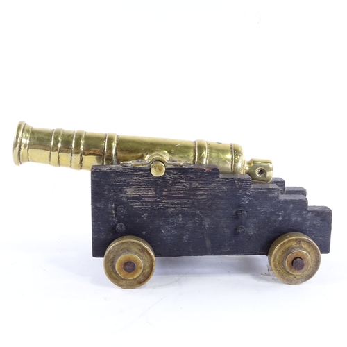 24 - A heavy brass table cannon on wooden base, overall length 24cm.