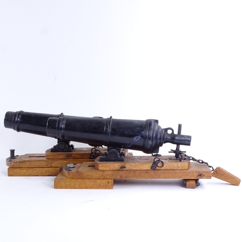 28 - A pair of cast-iron barrelled model cannons on stained oak stands, overall barrel length 28cm, base ... 