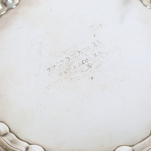 78 - A George V silver salver, circular form with scalloped rim raised on three acanthus leaf feet, with ... 
