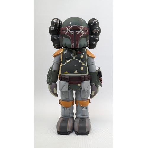 Kaws (American 1974-), 'Boba Fett', 2013, painted cast vinyl figure, stamped to the underside of the feet with the Artist's name and manufacturing details, manufactured by Medicom Toy; 24.8cm tall.
KAWS is an American graffiti artist and designer known for his toys, paintings, and prints. Born Brian Donnelly on November 4, 1974 in Jersey City, NJ, KAWS graduated with a BFA from the School of Visual Arts in New York. Since Graduating KAWS has become one of the most prominent artists in his field collaborating with well world-famous artist and brands such as Medicom, Kanye West, Pharrell Williams, Hennessy and the list goes on. His companion sculptures can be found all over London to Doha

Condition - Aerial Missing