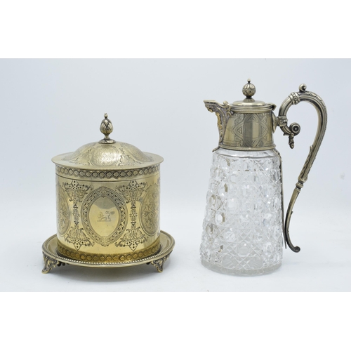 220A - An ornate silver-plated and glass claret jug together with a silver plated biscuit barrel raised on ... 