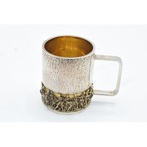 249 - Stuart Devlin: A silver and silver gilt tankard / cup with figural decoration to the bottom half of ... 