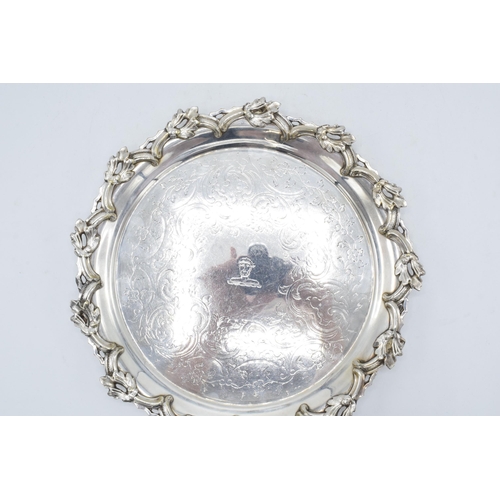 210O - A large silver plated salver raised on three ornate feet with unusual decoration. 26cm wide.