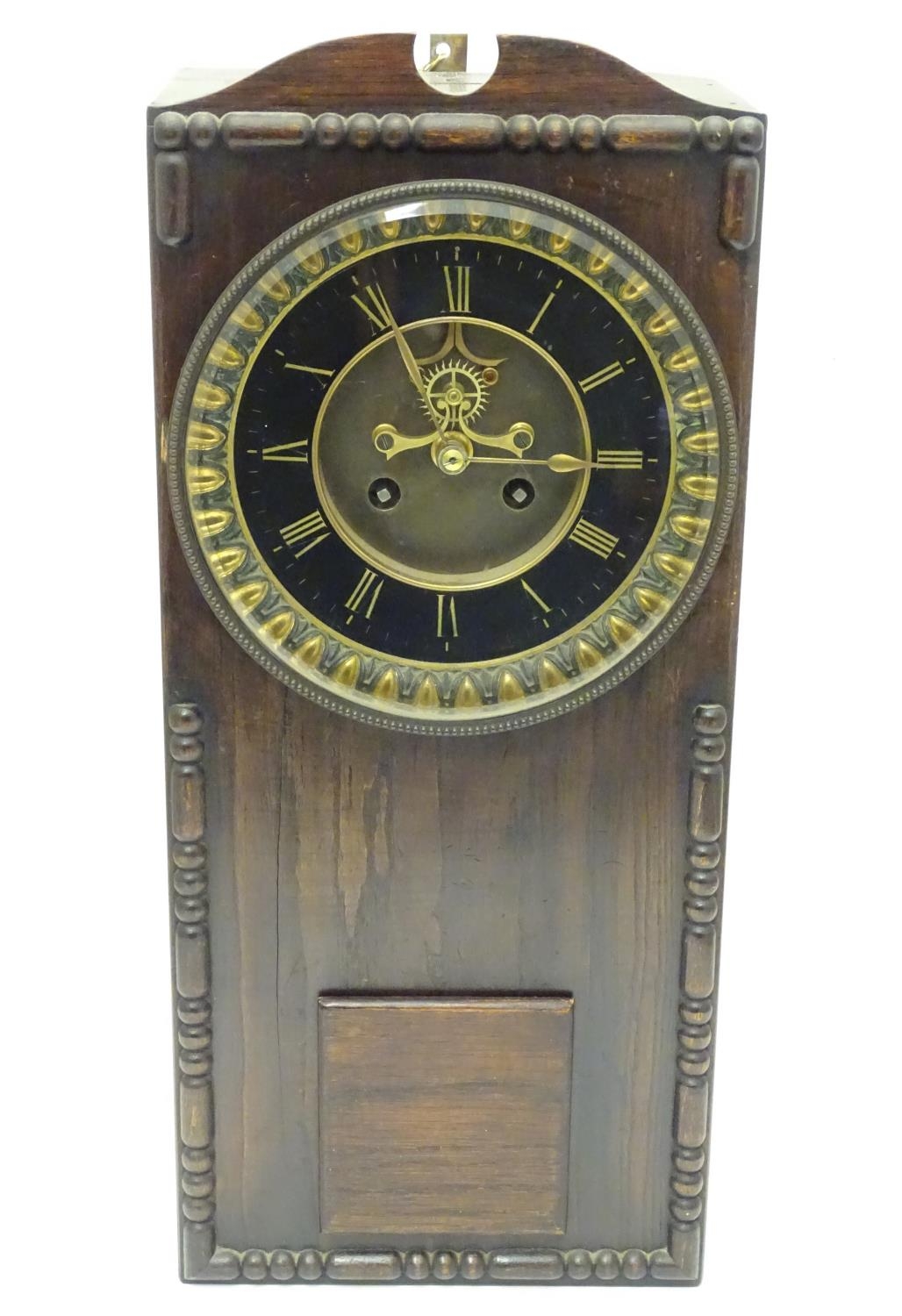 An Edwardian wall clock, the stained oak case housing a black and gilt