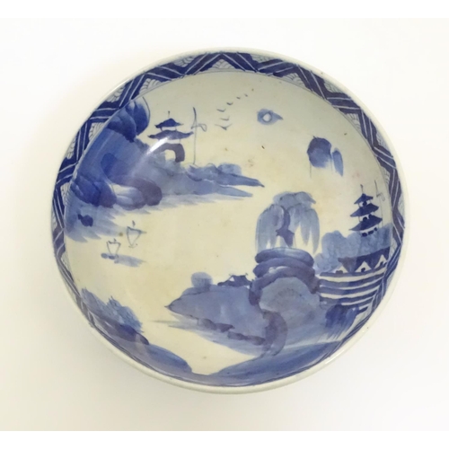 15 - A Chinese blue and white bowl with hand painted decoration depicting an Oriental landscape with pago... 