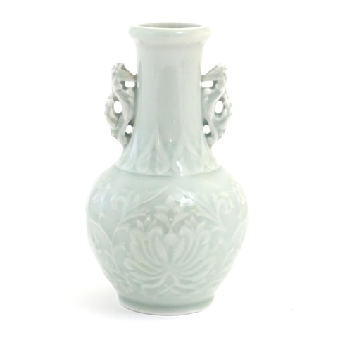 30 - A Chinese celadon green baluster vase with twin handles and stylised foliate design. Approx. 6 1/4