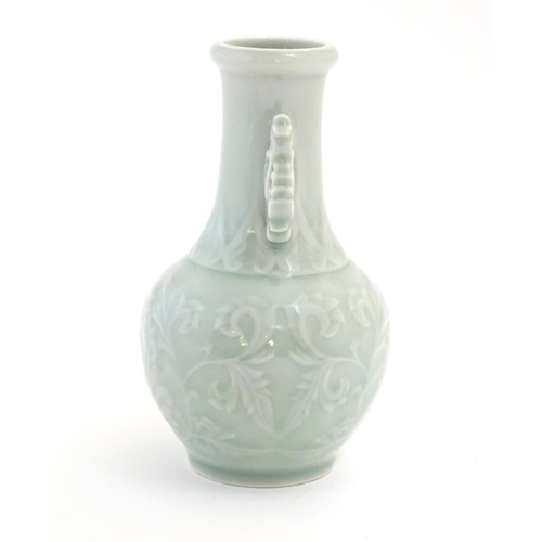 30 - A Chinese celadon green baluster vase with twin handles and stylised foliate design. Approx. 6 1/4