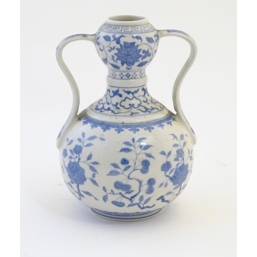 3 - An Oriental blue and white double gourd vase with twin handles decorated with scrolling floral and f... 