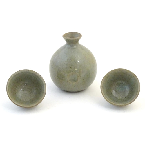43 - A studio pottery Japanese saki set with a crackle glaze, comprising a saki bottle with pinch detail ... 