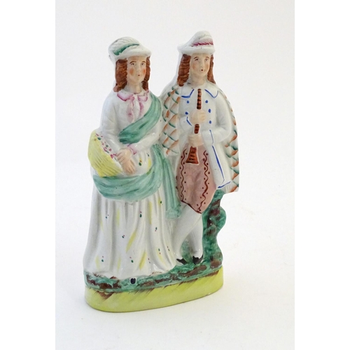 55 - A Staffordshire pottery figural group depicting two figures, one with a basket of flowers, the other... 