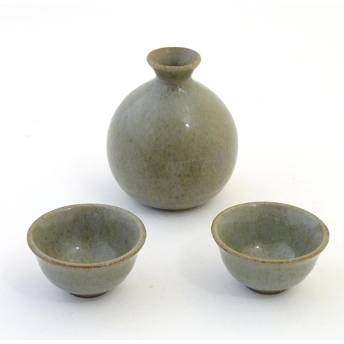 58 - A studio pottery Japanese saki set with a crackle glaze, comprising a saki bottle with pinch detail ... 
