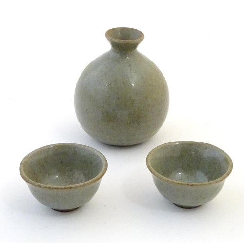 58 - A studio pottery Japanese saki set with a crackle glaze, comprising a saki bottle with pinch detail ... 