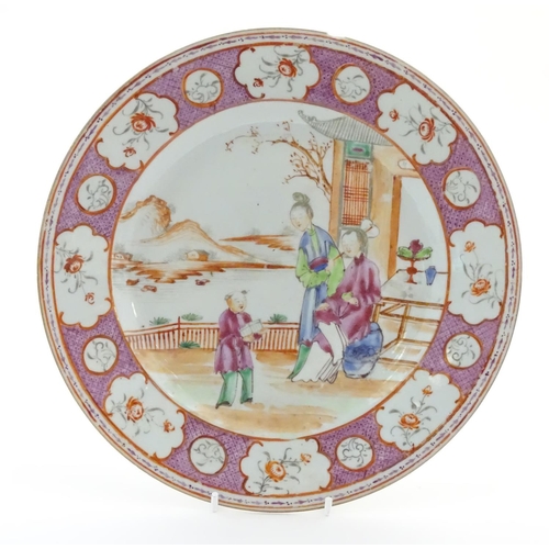 17 - A Chinese famille rose plate depicting figures on a garden terrace with a mountainous landscape beyo... 