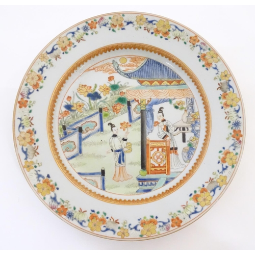 19 - A Chinese plate depicting two ladies in a garden terrace with flowers, foliate, vases, etc. Approx. ... 