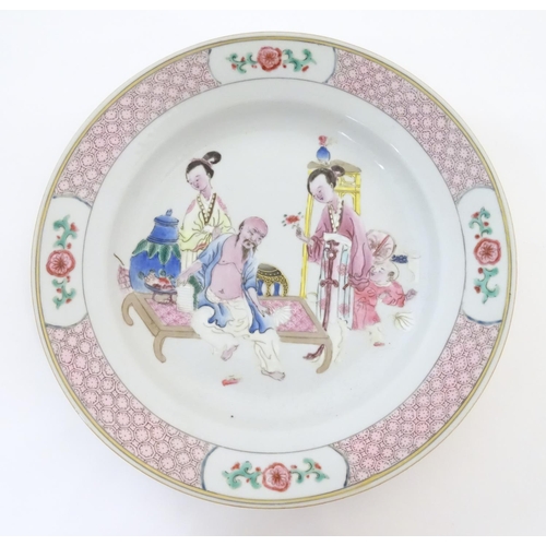 23 - A Chinese famille rose plate decorated with an interior scene with an elderly scholar on a day bed w... 
