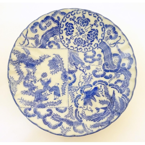 32 - An Oriental blue and white plate decorated with figures and scrolling flowers and foliage. With blue... 