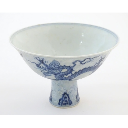 33 - A Chinese blue and white dragon stem bowl with a raised foot. The bowl decorated with two dragons am... 