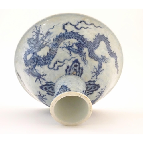 33 - A Chinese blue and white dragon stem bowl with a raised foot. The bowl decorated with two dragons am... 