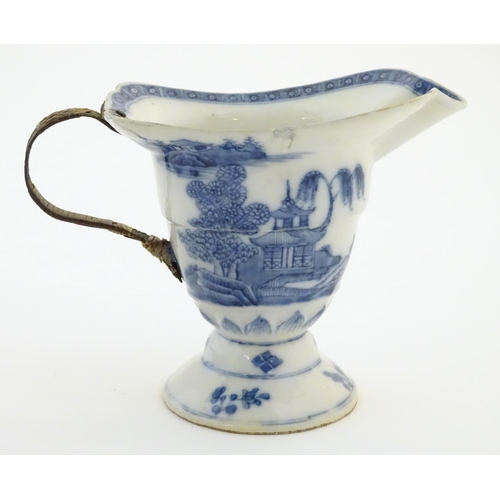 42 - A helmet jug with blue and white decoration with a stylised landscape scene with pagodas, blossom tr... 