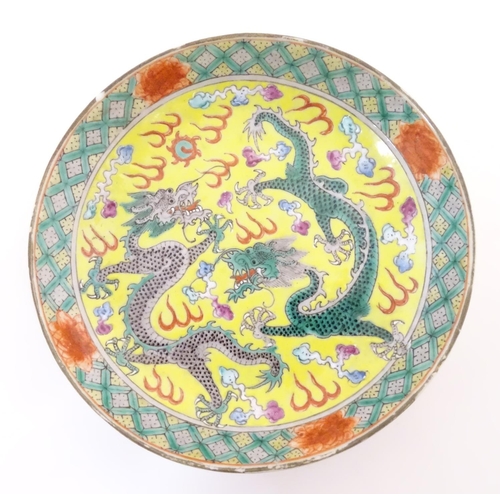 44 - Three Oriental items, comprising a plate with a yellow ground decorated with dragons and a flaming p... 