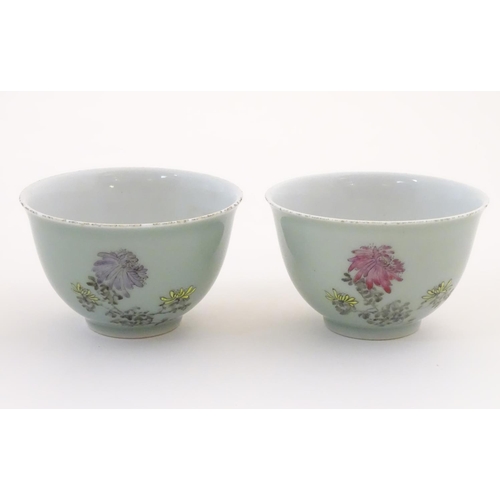 45 - A pair of Chinese tea bowls decorated with flowers and Oriental script. Character marks under. Appro... 