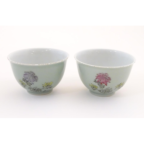 45 - A pair of Chinese tea bowls decorated with flowers and Oriental script. Character marks under. Appro... 