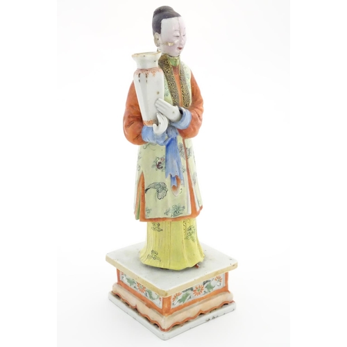 56 - An Oriental porcelain model of a male figure wearing a kimono with butterfly and floral detail holdi... 