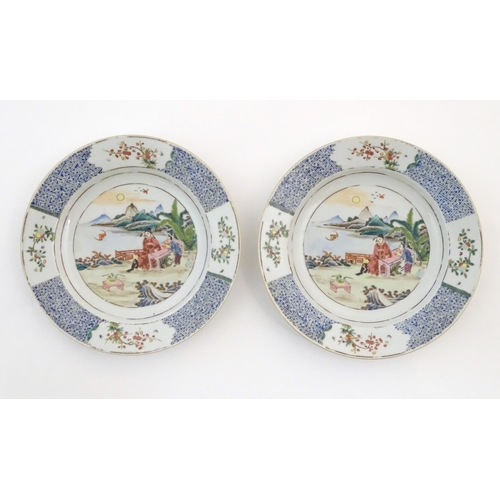 42 - A pair of Chinese plates depicting a two figures in a garden watching a bat, with sea and mountains ... 