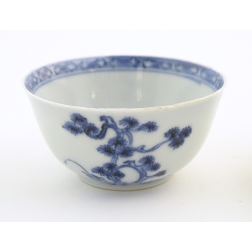 11 - A Chinese Nanking Cargo blue and white tea bowl and saucer, decorated with pine trees and banded bor... 