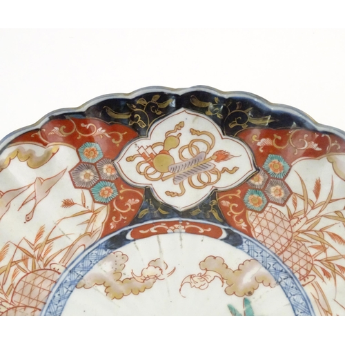 37 - An Oriental charger with scalloped edge in the Imari palette decorated with a stylised censor on sta... 