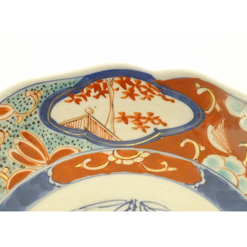 38 - A Japanese plate decorated in the Imari palette with stylised flowers and foliate detail. Character ... 
