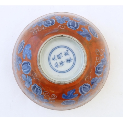 27 - A Chinese bowl with a red ground decorated with vine leaves and gourds. Character marks under. Appro... 