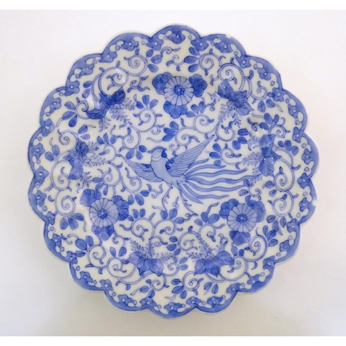 41 - An Oriental blue and white plate with scalloped edge decorated with a stylised exotic pheasant bird ... 