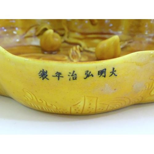 18 - A Chinese fluted edged yellow brush wash dish with relief bat and fruit decoration. Character marks ... 