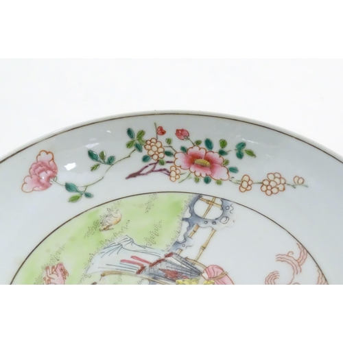19 - A Chinese famille rose plate decorated with a woman holding a fan in a garden terrace with a young a... 