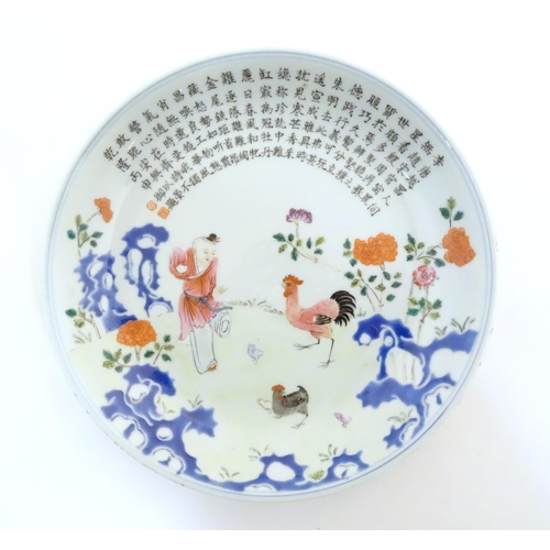 21 - A Chinese famille rose plate decorated with a figure, a cockerel, hen and chicks in a garden with fl... 