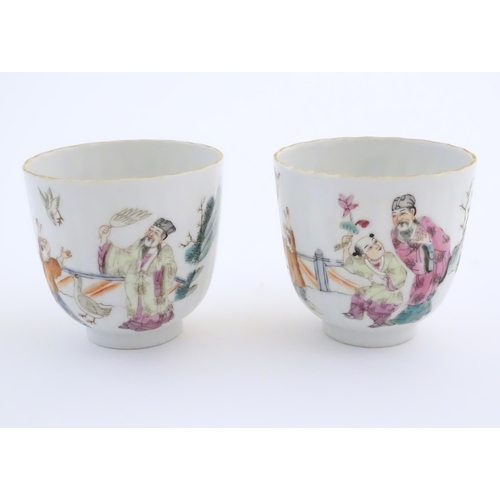 46 - A pair of Chinese tea cups decorated with figures in a garden terrace with two birds. Character mark... 