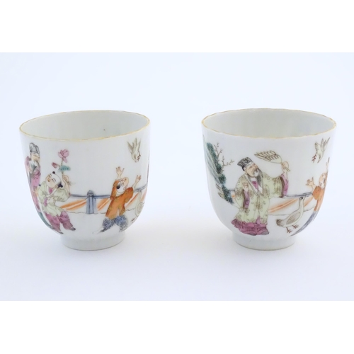 46 - A pair of Chinese tea cups decorated with figures in a garden terrace with two birds. Character mark... 