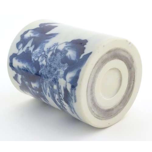49 - A Chinese blue and white brush pot of cylindrical form decorated with a stylised landscape with moun... 