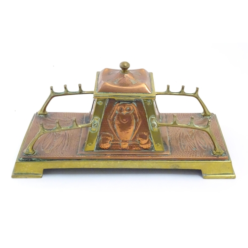 An Arts and Crafts hammered copper and brass standish, the central tapering inkwell with embossed owl decoration, flanked by Art Nouveau foliate detail. Marked Fisher, 188 Strand under. Approx. 4 3/4" high x 9 3/4" wide x 5" deep