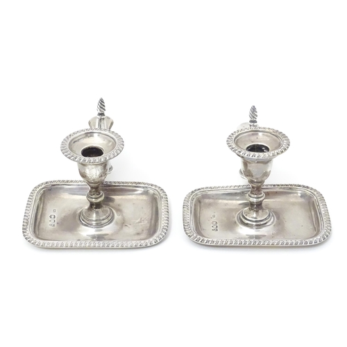 295 - A pair of small Victorian silver chambersticks / taper stick holders with gadrooned detail, each wit... 