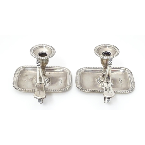 295 - A pair of small Victorian silver chambersticks / taper stick holders with gadrooned detail, each wit... 