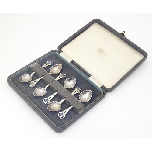A set of six Arts & Crafts silver tea spoons with hammered decoration to bowls and pierced terminals set with stone cabochon, hallmarked Birmingham 1927, maker Winifred King & Co. Spoons approx. 3 1/2" long