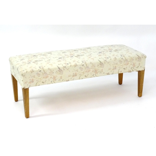 2042 - A 20thC footstool with floral upholstery and standing on four tapering legs. 48