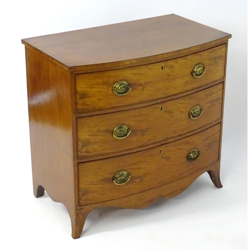 1938 - A late Georgian mahogany chest of drawers with a bow front above three long drawers with brass embos... 