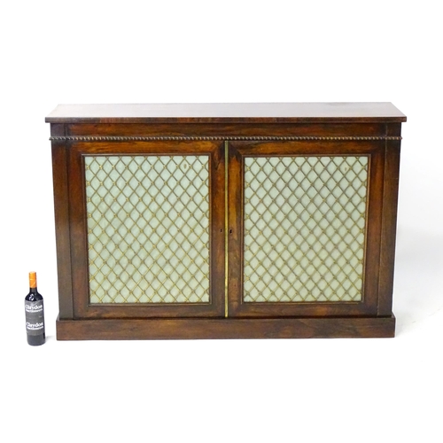 1957 - A Regency rosewood bookcase with a rectangular top above egg and dart mouldings with brass grilled d... 