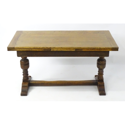 2041 - An early 20thC oak draw leaf table with a trestle style base. 54