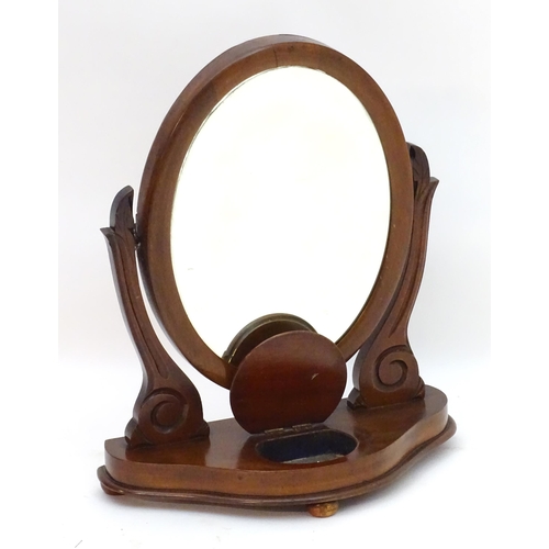 30 - A Victorian mahogany toilet mirror with an oval mirror and shaped surrounds above a moulded base wit... 